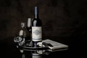 bottle of Cabernet Sauvignon with a glass of wine and wine service accessories